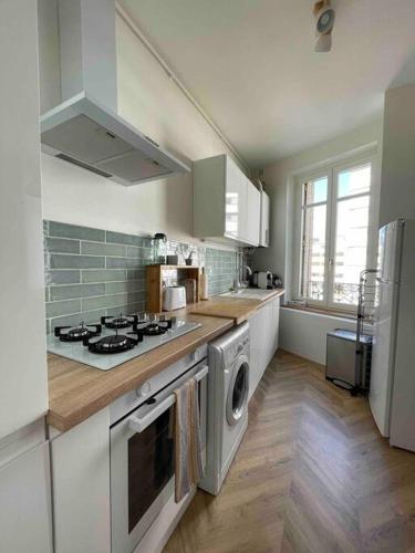une cuisine avec une cuisinière et une machine à laver dans l'établissement Cocon douillet près de la Gare., à Nancy
