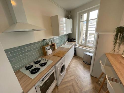 Il comprend une cuisine équipée d'une cuisinière. four supérieur à côté d'un comptoir dans l'établissement Cocon douillet près de la Gare., à Nancy