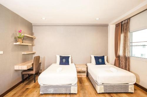 two beds in a room with a table and a desk at Blue cafe Apartments in Chiang Mai