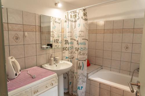 a bathroom with a sink and a tub and a shower curtain at Christine's House in Nafpaktos