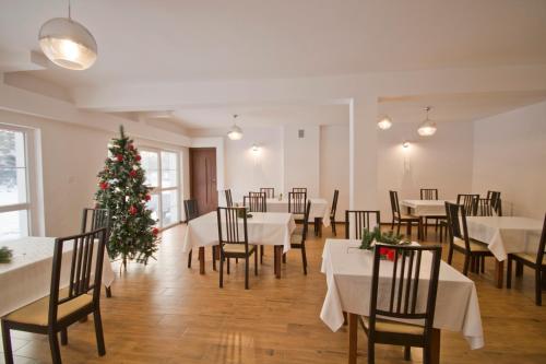 a dining room with a christmas tree and tables and chairs at U Gienka Pod Lasem in Święta Katarzyna
