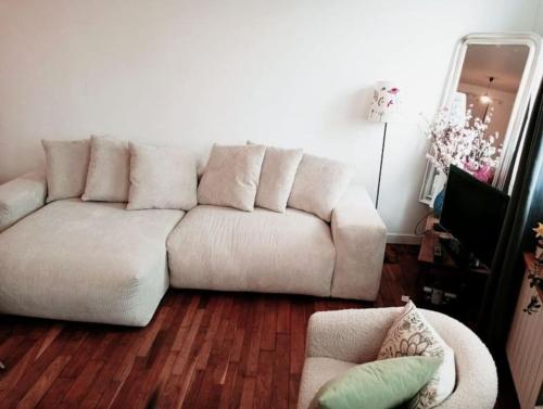 uma sala de estar com um sofá branco e pisos em madeira em Jolie Maison proche métro em Romainville