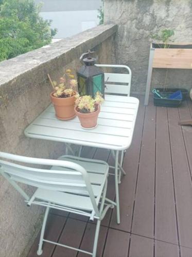 uma mesa branca e cadeiras num deque com plantas em Jolie Maison proche métro em Romainville