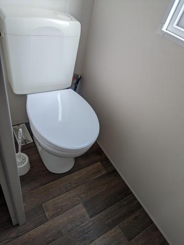 a white toilet in a bathroom with a wooden floor at Mobil Home Confort 4 Places in Biesheim
