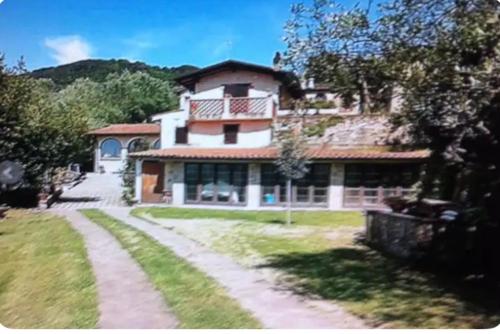 una gran casa blanca con un camino delante de ella en Villa Oscar con piscina e palestra, en Camaiore
