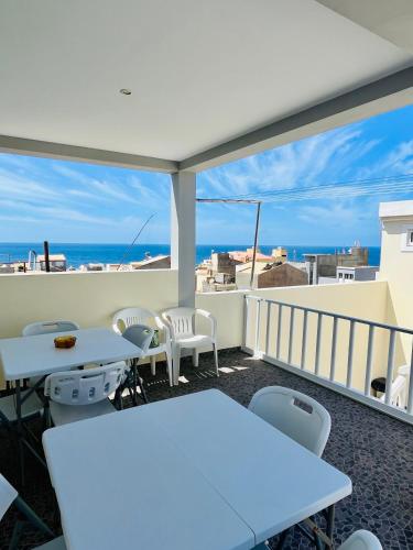 a balcony with tables and chairs and a view of the ocean at Casa BB&Djassi - room L in Ponta do Sol