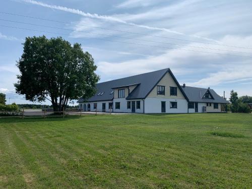 a large white house with a tree in a field at Hiiumaa Sõru Puhkemaja in Sõru