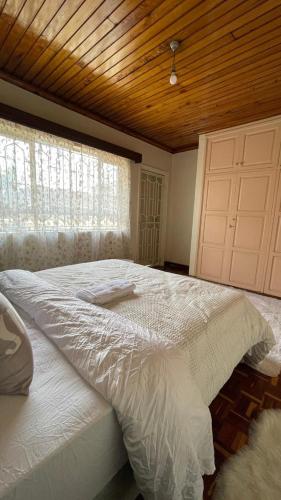 1 dormitorio con 1 cama blanca grande y techo de madera en Riverside Villa en Nairobi