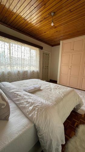 a bedroom with a large white bed with a wooden ceiling at Riverside Villa in Nairobi