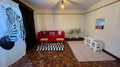 a living room with a red couch and two chairs at Riverside Villa in Nairobi