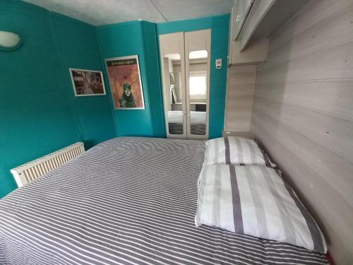 - une chambre avec un grand lit aux murs bleus dans l'établissement MAISON AVEC VUE MER, à Saint-Côme-de-Fresné