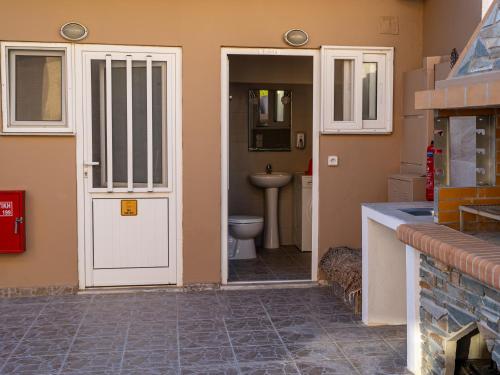 a bathroom with a white door and a toilet at Villa Nektarina in Afantou