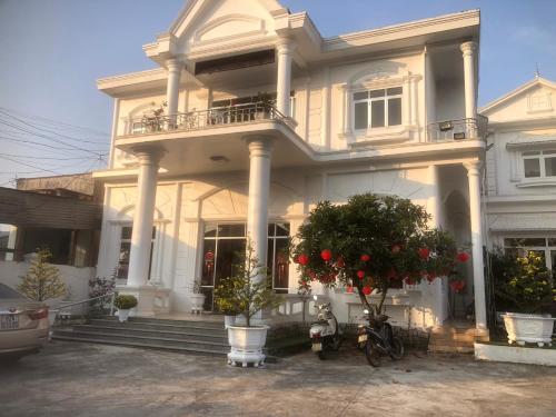 Biały dom z dwoma motocyklami zaparkowanymi przed nim w obiekcie KHÁCH SẠN PHƯƠNG DUNG w mieście Dak Rơleang