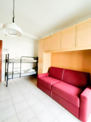 a red couch in a living room with a bed at Viale Aurora in Bibione