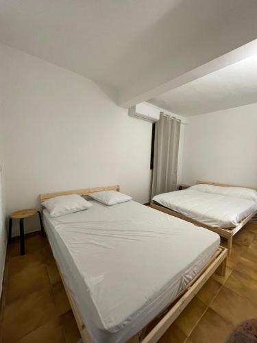 two beds in a room with white walls at Chez eliot in Vico