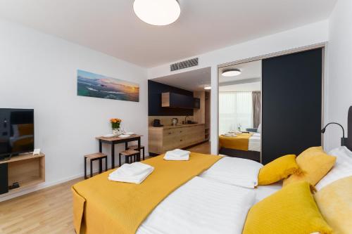 a bedroom with a large white bed with yellow pillows at Apartament Prywatny Seaside Park 649 in Kołobrzeg