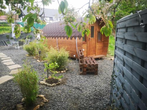 a small wooden cabin with a bench in a yard at Agroturystyka u Kozdryka in Leśna