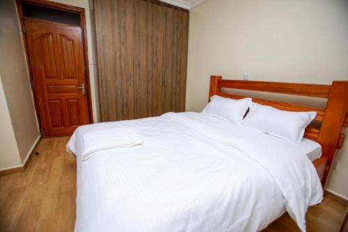 a bedroom with a large white bed with a wooden headboard at WHITE LOTUS EXECUTIVE APARTMENT in Meru