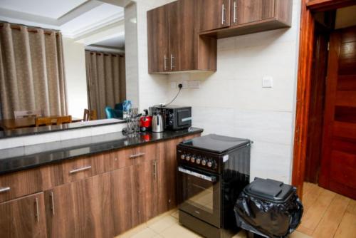 a kitchen with wooden cabinets and a black stove at WHITE LOTUS EXECUTIVE APARTMENT in Meru