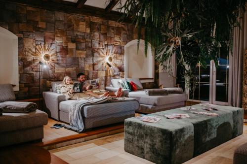 a man and woman sitting on a couch in a living room at Hotel Salzburger Hof Zauchensee in Zauchensee