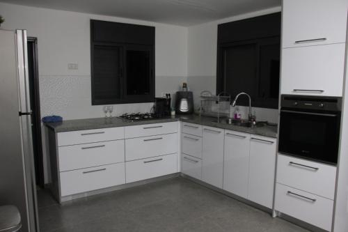 a kitchen with white cabinets and a stove top oven at וילה במעיין in Gid‘ona