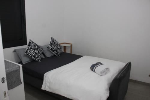 a bed with black and white pillows on top of it at וילה במעיין in Gid‘ona
