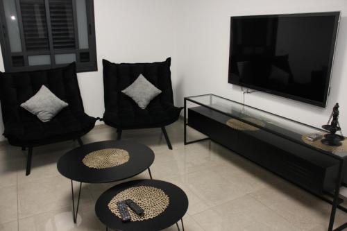 sala de estar con 2 sillas y TV de pantalla plana en וילה במעיין, en Gid‘ona
