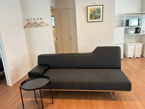 a black couch in a living room with a stool at Aile HouseⅢ GS in Takasaki