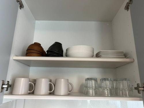 a white shelf with plates and cups and glasses at Aile HouseⅢ GS in Takasaki