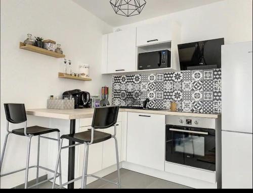 une cuisine avec des armoires blanches et un comptoir avec des tabourets dans l'établissement modern cozy apartment, à Montreuil