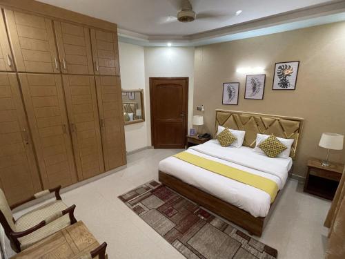 a bedroom with a large bed and a chair at Safari Hotel in Islamabad