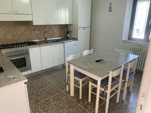 カランブローネにあるCasa al mareの白いキャビネット、テーブルと椅子付きのキッチンが備わります。