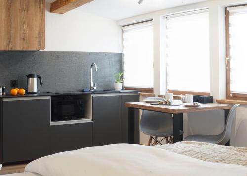 a kitchen with a sink and a table with chairs at Kamienica Na Nowo Apartamenty Warszawska in Mrągowo