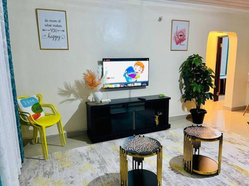 uma sala de estar com televisão e duas cadeiras em Mancave em Eldoret