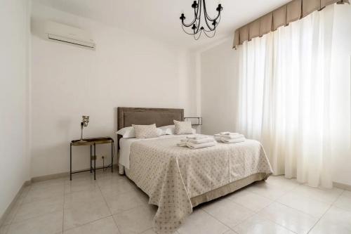 a white bedroom with a bed and a chandelier at Casa Dedalu Confortevole Attico a pochi passi dal centro in Fasano