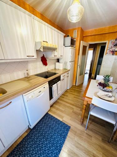 une cuisine avec des placards blancs et une table avec un tapis bleu dans l'établissement Spacieux 2 chambres 65m2 climatisé au village médiéval entre Nice et Antibes, à Villeneuve-Loubet