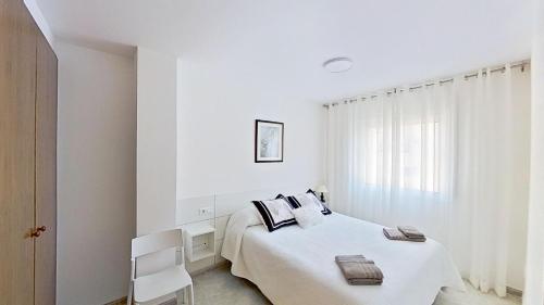 een witte slaapkamer met een bed en een raam bij Apartamento vistas al mar, segunda línea 3 habitaciones in Sant Carles de la Ràpita