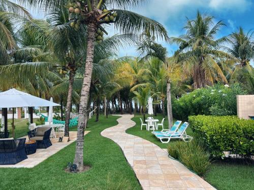 een resort met palmbomen en stoelen en een loopbrug bij Casa Sonho da praia beira-mar 04 suítes in Barra de Santo Antônio