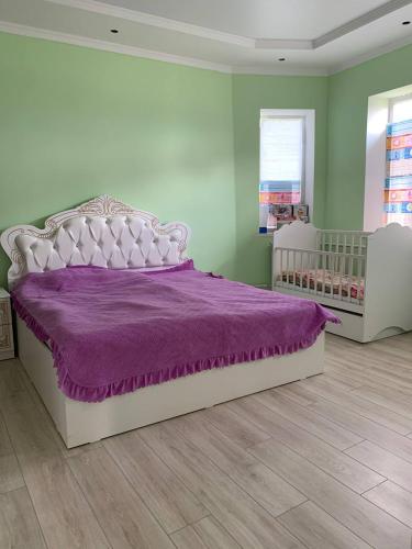 1 dormitorio con cama blanca y edredón morado en Бурана уютный дом, 