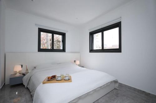 a white bedroom with a white bed with two windows at וילת פאר בקו ראשון לים in Ashdod