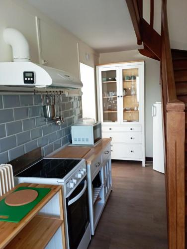 Il comprend une cuisine équipée d'une cuisinière. four supérieur à côté d'un comptoir dans l'établissement gite du puits, à Bernières-dʼAilly