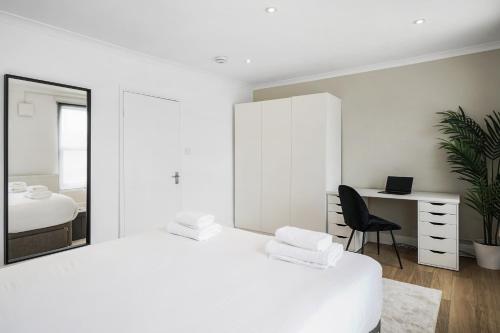 a white bedroom with a bed and a desk and a chair at 2 Bed Apt in Greenwich near O2 in London