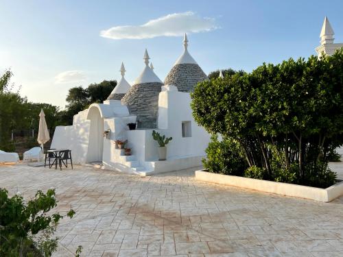 ein weißes Gebäude mit Bäumen und einer Terrasse in der Unterkunft VITA VIVET TRULLO in San Michele Salentino
