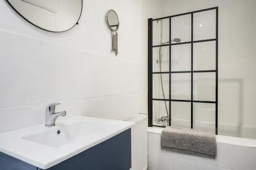 a white bathroom with a sink and a mirror at 2 Bed Apt in Greenwich near O2 in London