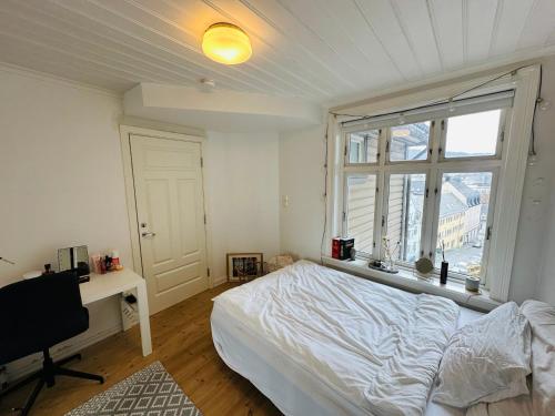 1 dormitorio con cama, escritorio y ventana en Sjarmerende bolig like ved togstasjonen, en Bergen