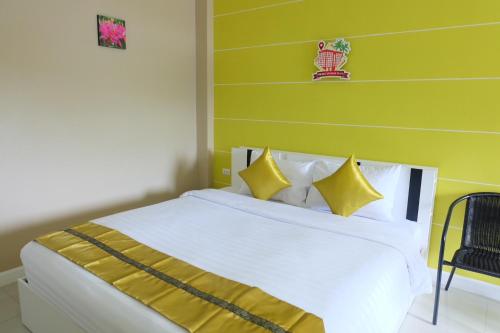 een slaapkamer met een wit bed en gele muren bij Phuket Andaman Place ภูเก็ตอันดามันเพลส in Phuket