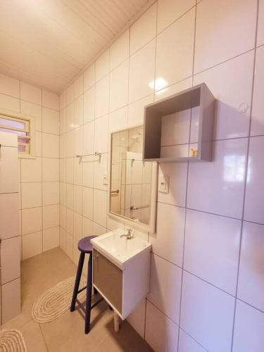 a bathroom with a sink and a mirror and a stool at Casa da Vó Hospedagem Afetiva in Bento Gonçalves