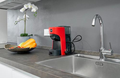 Una batidora roja sobre la encimera de la cocina, junto a un fregadero. en Bellavista, en Arzachena