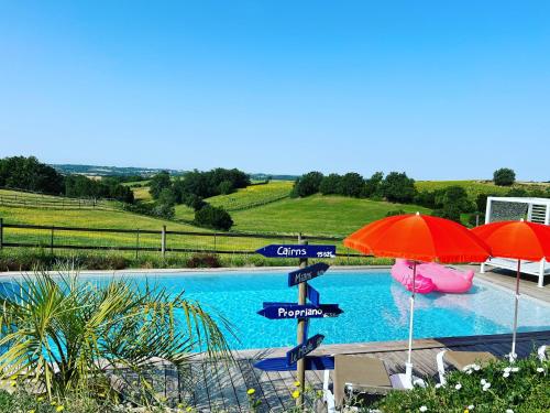 une piscine avec des parasols et une piscine dans l'établissement Domaine Horizon, à Toulouse