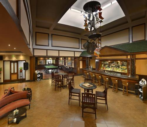 a lobby with a bar and tables and chairs at The LaLiT Golf & Spa Resort Goa in Canacona